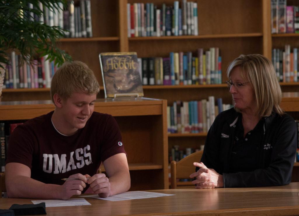 Senior+Ben+Sloan+signs+to+swim+at+the+University+of+Massachusetts+in+the+Free+State+library+in+December.+Coach+Annette+McDonald+looks+on+from+his+side.