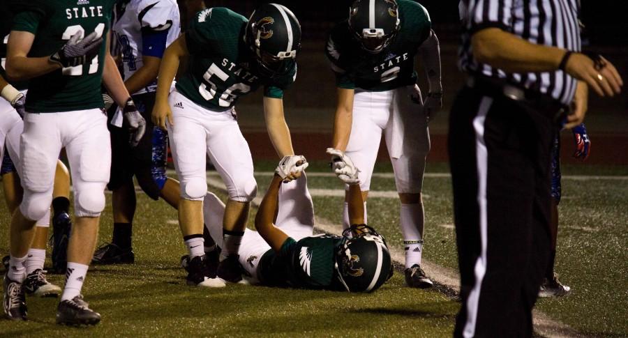 Seniors Jacob Allen and Joel Spain help a teammate to his feet during the varsity Homecoming game against Leavenworth. 