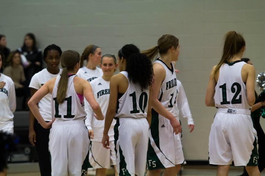 Waiting for the game to begin, members of the varsity girls basketball team chat with one another. Coach Bryan Duncan believes the teams chemistry is driving them in the right direction. They just seem to find the right mix of having fun and really competing hard, and I think that leads to success, Duncan said. 