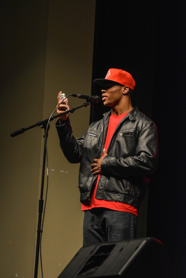 Reading from his phone, junior Khaury El-Amin shares his poem, Whats Up Dad? at the talent show.