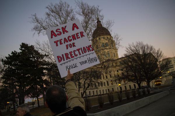 A member of KNEA holds up a sign during a protest at the capitol in Topeka. Sam Brownbacks plan to cut school funding resulted in marches and protests.