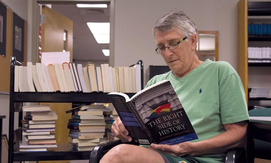 Reading one of her favorite books, The Right Side of History by Adrian Brooks, P.E. teacher Hopkins sits next to just one of several racks that will soon be unpacked into the library. 