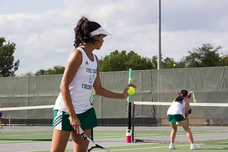 Looking across at her opponent, senior Dalma Olvera gets ready to serve at Free States dual meet against Mill Valley on September 17. Olvera plays soccer, a cut sport, and tennis, a non cut sport. 