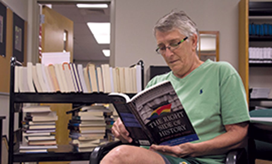 Reading one of her favorite books, "The Right Side of History" by Adrian Brooks, P.E. teacher Hopkins sits next to just one of several racks that will soon be unpacked into the library. 