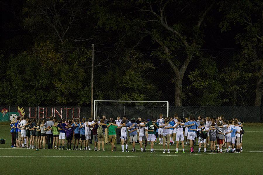 The varsity soccer team performs their ceremonial huddle after a home game. Fans and parents were encouraged to join.