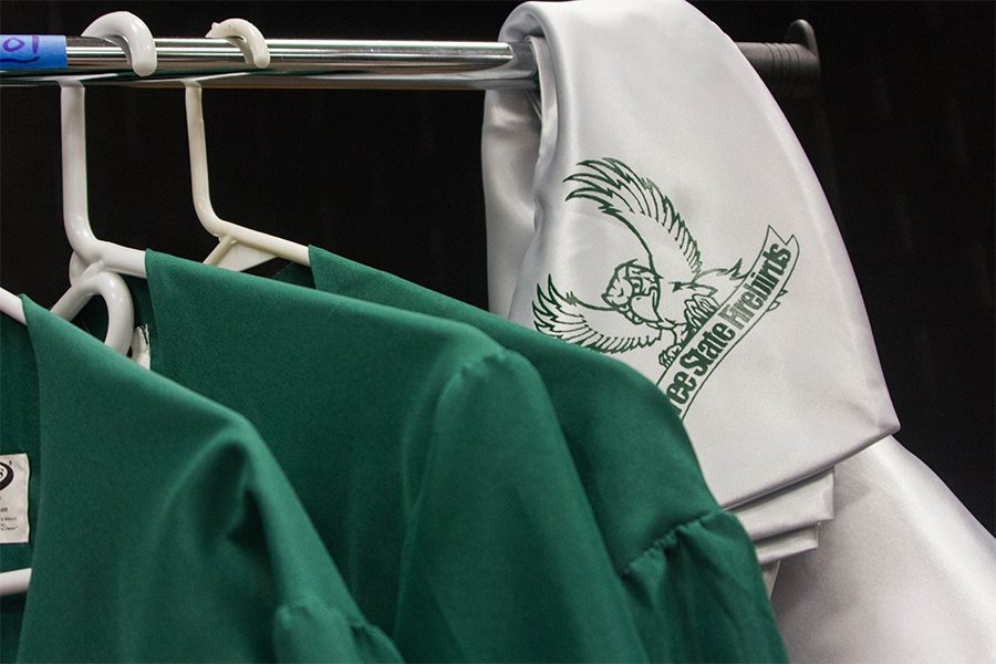 Gowns sit on a hanger in the Black Box. Seniors can avoid additional fees by using their siblings garments.