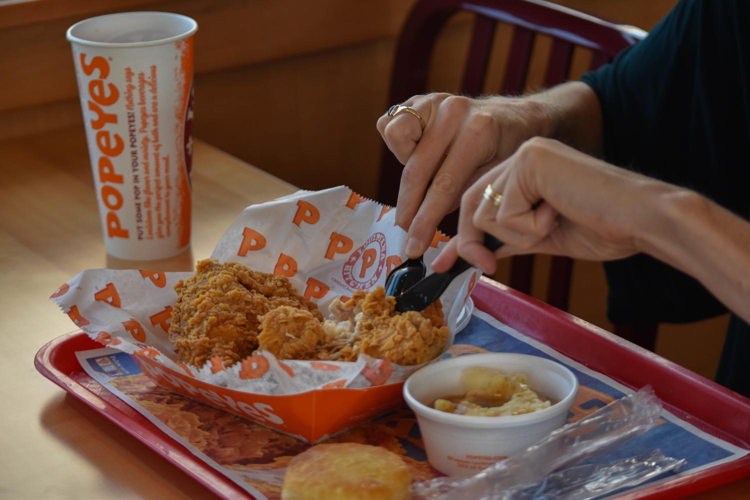 A+woman+cuts+into+her+chicken+at+Popeyes+Louisiana+Kitchen.