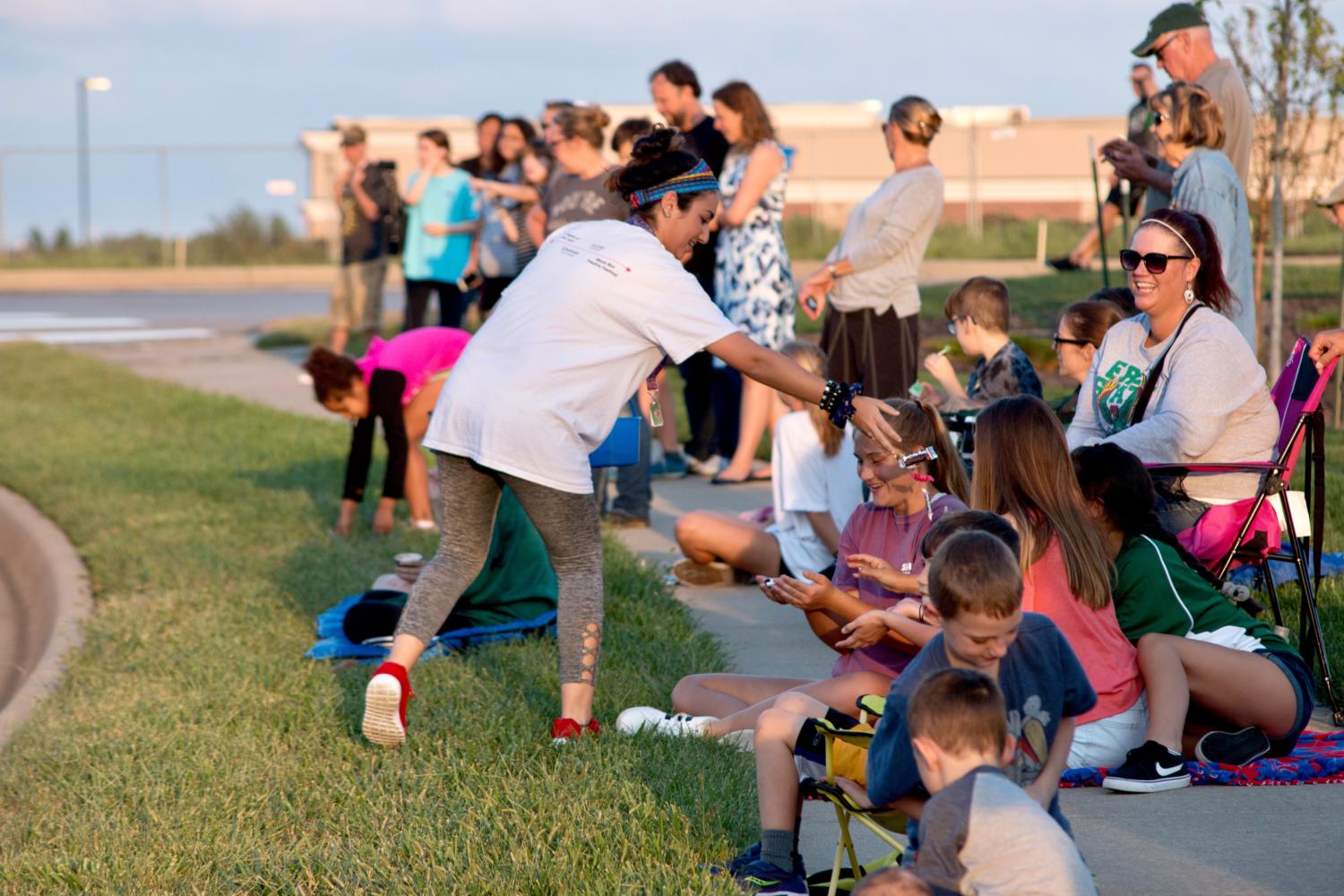 During the parade, sophomore Shaza Al Kassim hands out candy to young community members watching. Al Kassim was part of the theater club float, their theme was everything goes to help promote their upcoming musical.