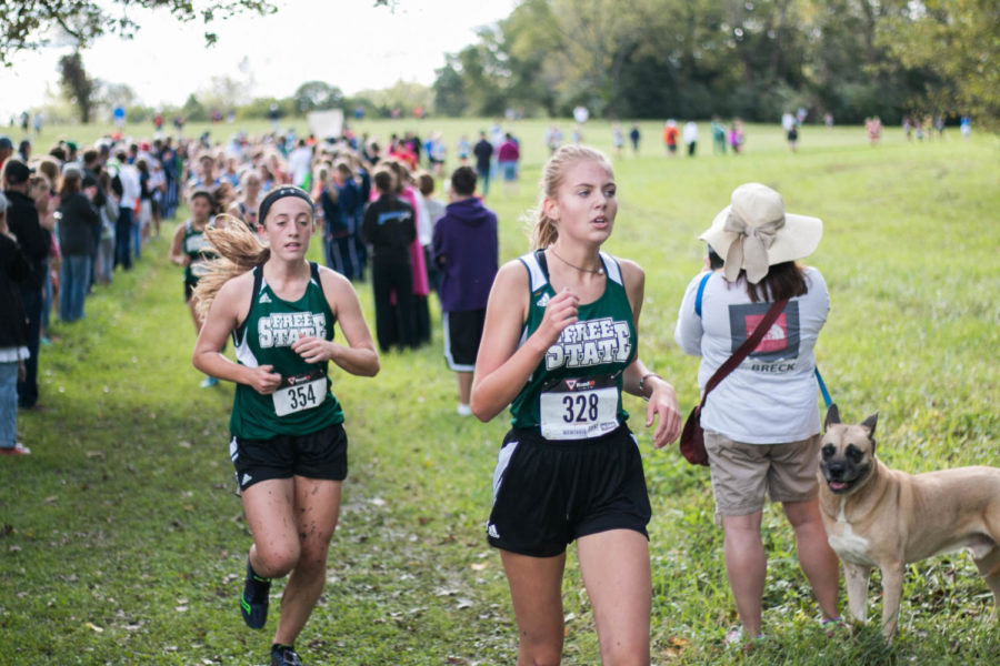 Sophomore Bella Crawford-Parker and senior Kate Odgers run past a dog. Crawford-Parker finished in 23:38.