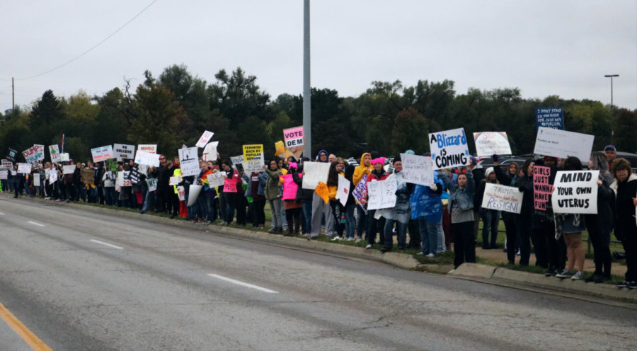 On the sidewalk outside the arena, approximately 500 people line up to protest the MAGA rally being hosted inside the Expocentre.