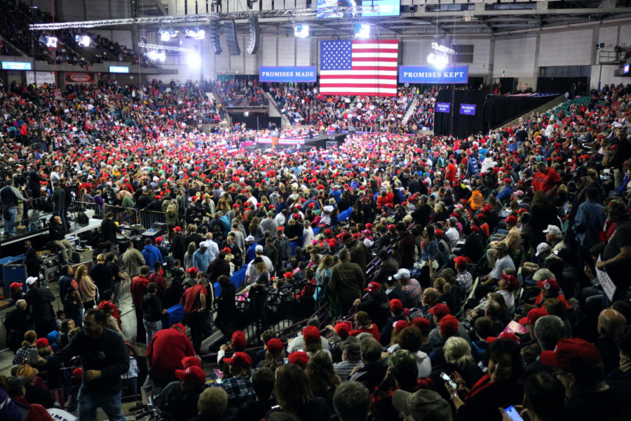 Filling the Expocentre, Trump supporters find their seats to catch a clear view of signs advertising Promises Made, Promises Kept. The arena was filled to capacity of 10,000, forcing some viewers to stand in the back and some to be denied entry to the event. 