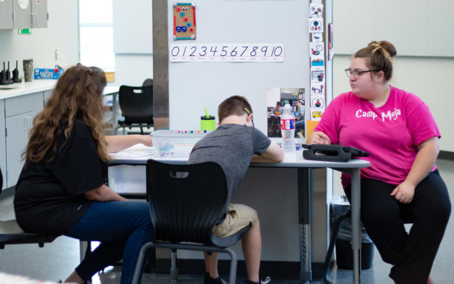 Junior Ethan Sigourney works on a project alongside his teachers. The SpEd program helps students develop different skills, including cooking and cleaning in the new kitchen across the hall. “[The students] cook, they do the laundry, and they clean up after themselves,” SpEd teacher Denise Posey said. 