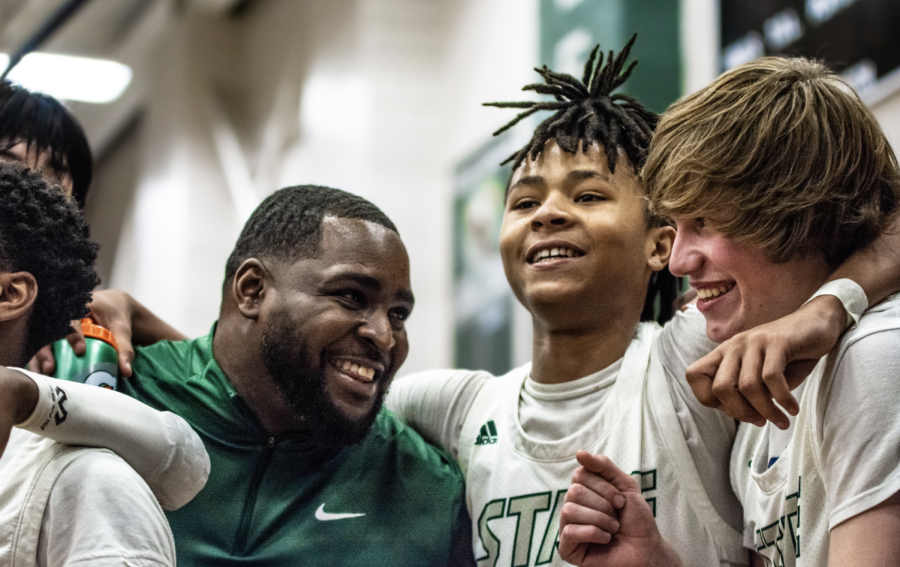 Varsity Boys Basketball head coach, Sherron Collins joins in with Cortez Overstreet and Zeek Brown in the traditional Alma Matter celebration played after the first home game win against Gardner-Egerton. Starting the season, one of Collins biggest goals was to connect with the players off the court on a personal level.