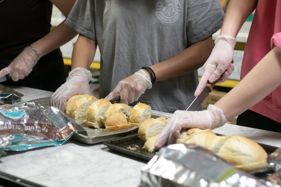 Junior Brynn Cordova, junior Jasmy Mavilla and sophomore Gayla Gao cuts bread. The club served spaghetti and garlic bread at the kitchen. 