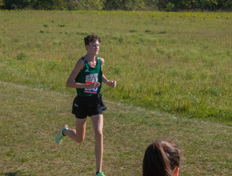Striding ahead, junior Blake Wholer attacks the final hill during his race. Wholer was a great role model to the underclassmen this season. “I try to bring good energy while still getting better and pushing both myself and my teammates every day” Wholer said. 