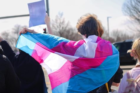 Student poses with a transgender flag during a student-organized walkout. Students from across the district walked out from class on March 28 to voice their opinions on the introduction of anti-trans bills in Kansas. ““[Trans] rights should be like anybody else’s rights: being protected, and being valued, because they are human rights, obviously,” event organizer junior Adriana Cazares said. 