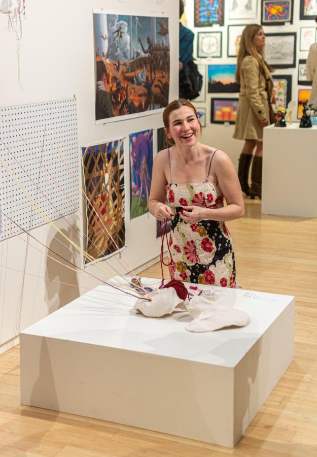 Senior Caroline Börk smiles as she works on one of her art pieces on display at the Lawrence Arts Center. Börk began her art journey at a young age by taking classes at the Arts Center Preschool. “Funny enough, that is where the [previous] exhibition was held...so, I both started and ended my Lawrence artist journey at the arts center,” Bork said.