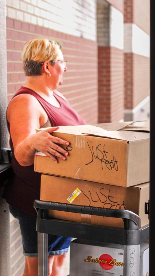 Awaiting pickup for a JustFood donation, cafeteria worker DJ Brockway stands with the cafeteria’s contributions of hamburger buns and juice. After lunch on Wednesdays and Fridays, the kitchen staff prepares and packages uneaten food to be collected by a JustFood employee.