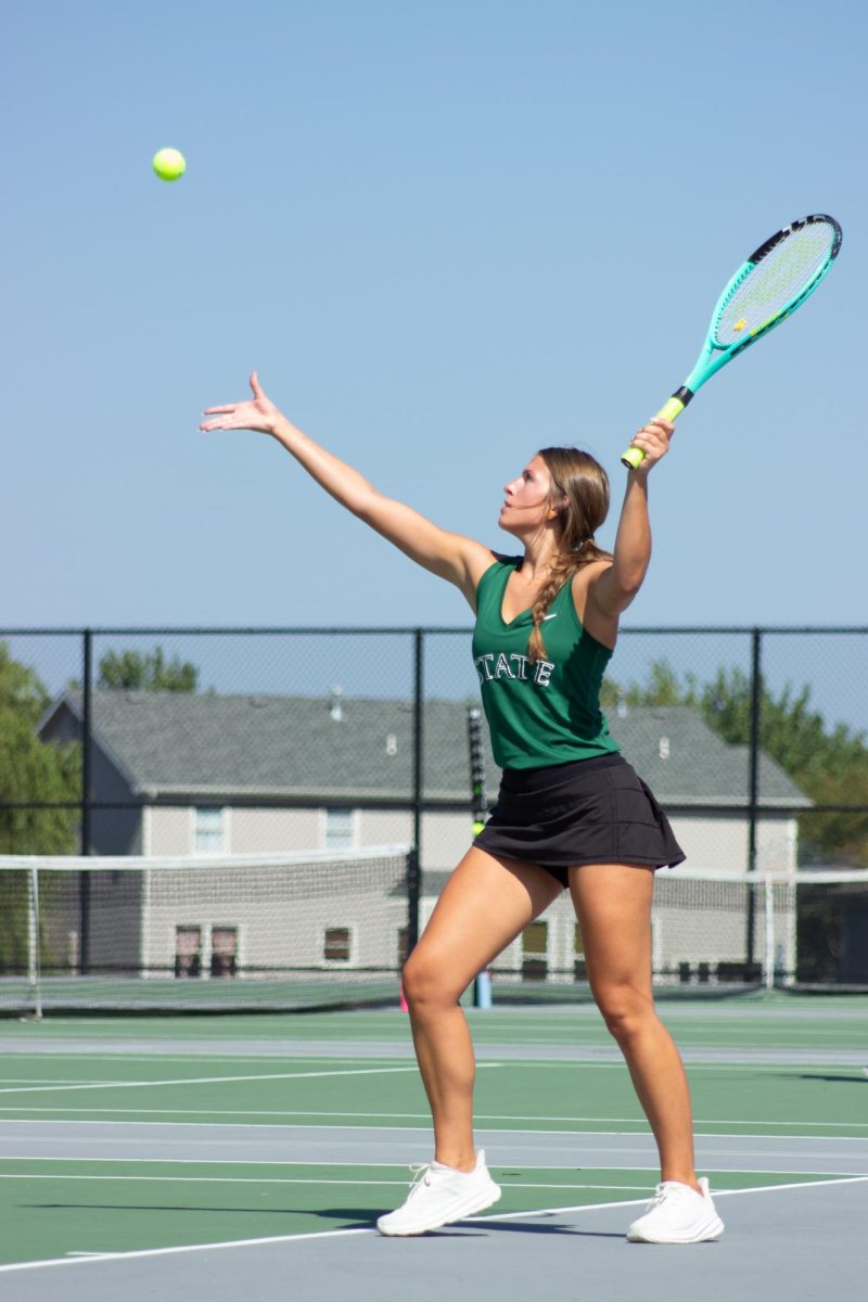 Serving the ball, senior Ava Holt attempts to win a point against a girl from Olathe West. Holt had a rough start to the match, however she was able to catch up to her opponent and win the game. “I couldnt have done it without all the amazing support from the sidelines,” Holt said.