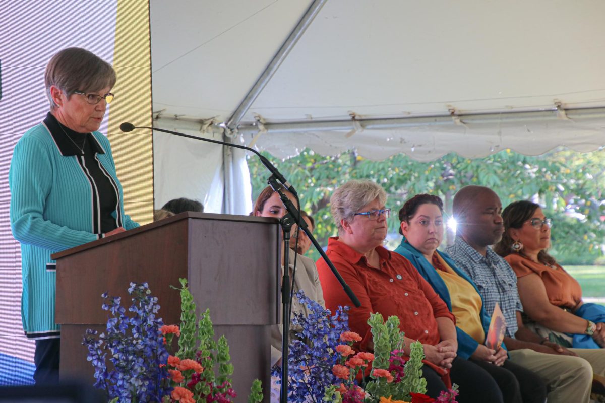 Governor Laura Kelly discusses how she will participate in the Kaw Nations commemoration of the Sacred Red Rock, Íⁿ’zhúje’waxóbe. Seated to the right are Sydney Pursel, Lawrence City Commissioner Amber Sellers, Mayor Lisa Larsen and City Commissioner Courtney Shipley.
