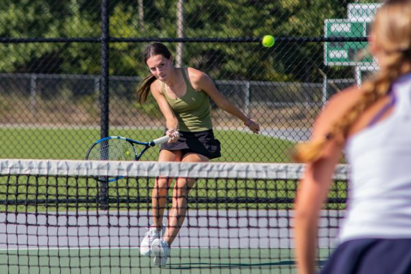 Running towards the ball, junior Delaney Bruhns works to win a point against her opponent.