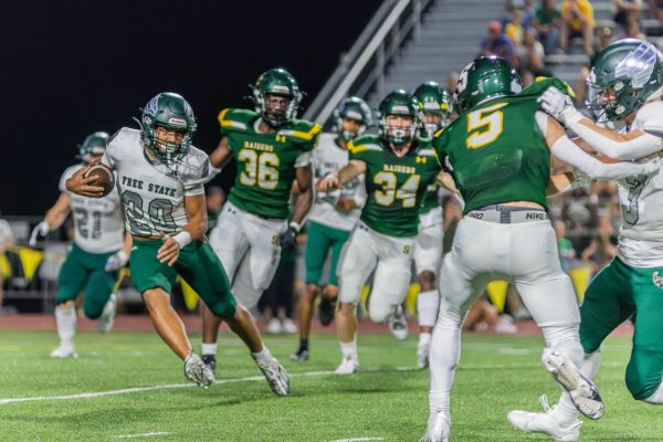 Dodging past opponents of Shawnee Mission South, junior Noah Simpson runs the ball down the field. The Free State Varsity Football team beat Shawnee Mission South 49-24 tonight, and currently has a season record of 5-0.