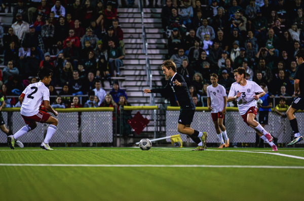 Junior James Spear dribbles the ball through Lawrence High players. The junior, who is playing his first year on varsity, acts as a defender.