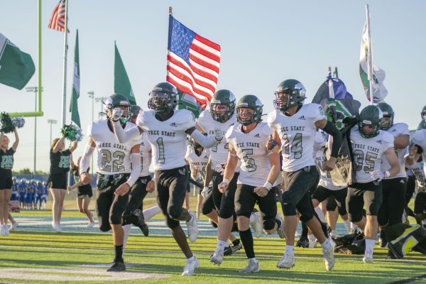 The varsity football players cheer while running onto the field before their away game against Olathe West. Free State beat Olathe West 47-29 at their first game of the season on Thursday, Aug. 31.