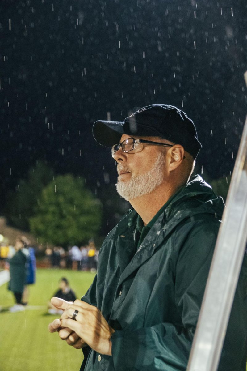 Standing in the rain, Band Director Eric Bradshaw watches the marching band show during halftime. New to the district, Bradshaw set a lot of goals for the program. Getting the performance at the first home game with everything being so new, Bradshaw said. That was a big goal for the program.