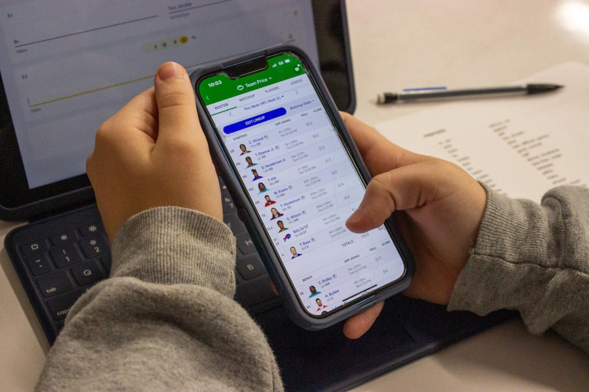  On her phone, senior Cydnee Price looks through the lineup roster for her fantasy football team. 