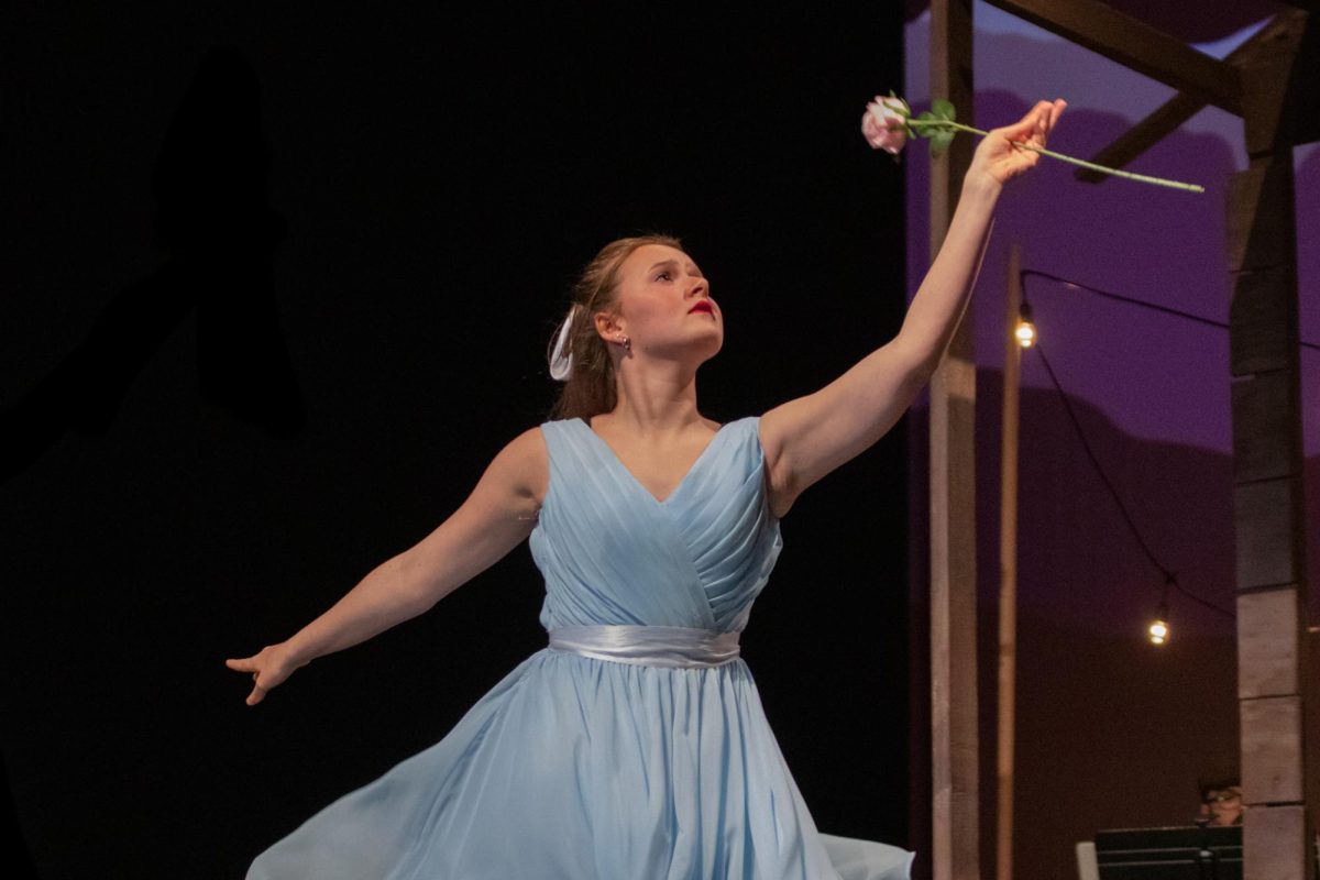 Dancing across the stage, sophomore Joy Malin lifts a rose in the air.