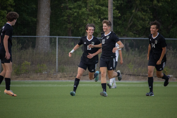 Celebrating with his teammates, senior Drew Rosenthal runs toward the student section after a goal at a varsity soccer game on Sept. 5.