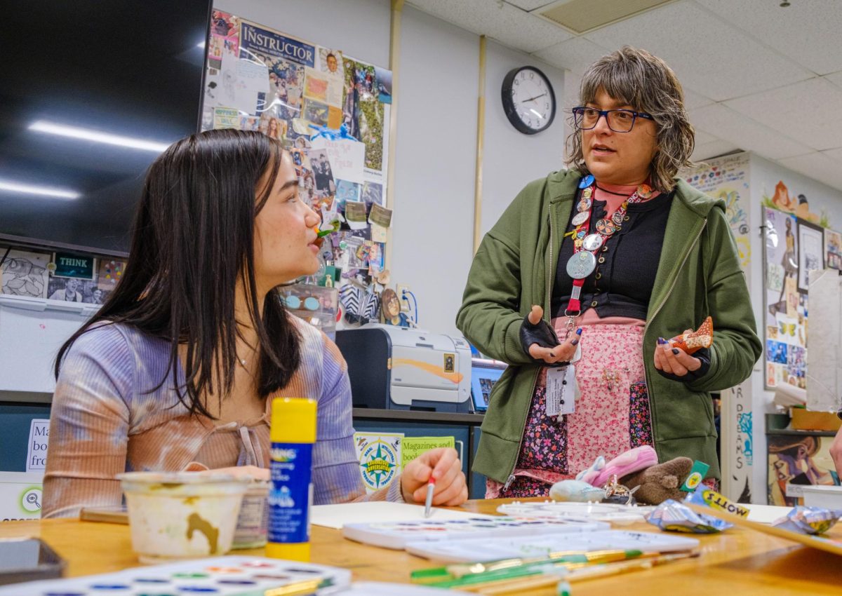 Teacher Rachel Downs advises senior Chloe Mure-Limburg on a water color project in one of Downs art classes.