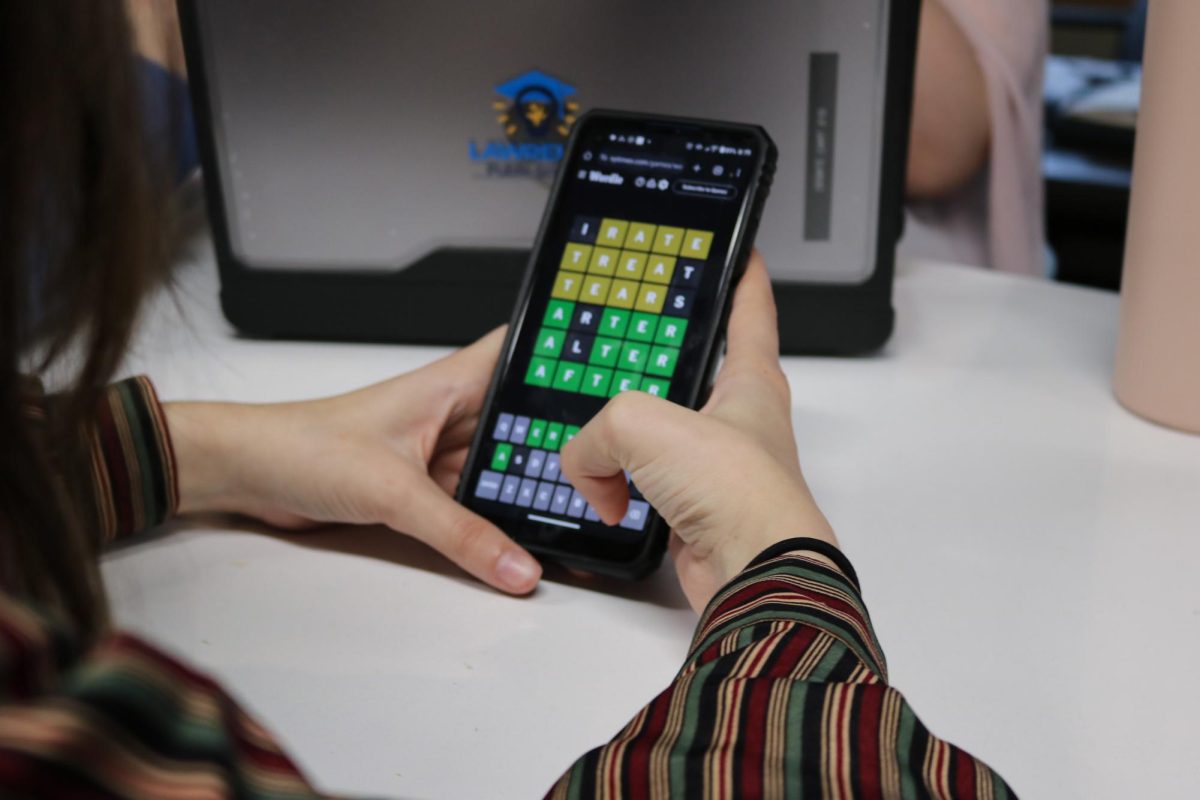 A student plays the New York Times game “Wordle” on their phone. Many students have stopped playing the game since it has faded.