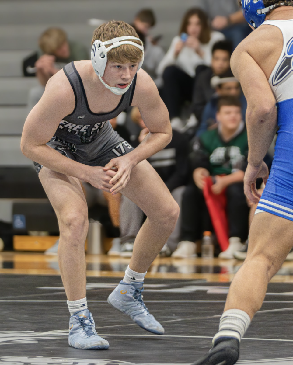 On the mat, sophomore Zane Shaw circles his opponent at the beginning of a match.