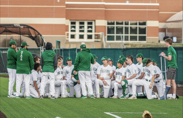 The varsity baseball team kneel together after winning the first home game of the 2023 season on March 23, 2023.
