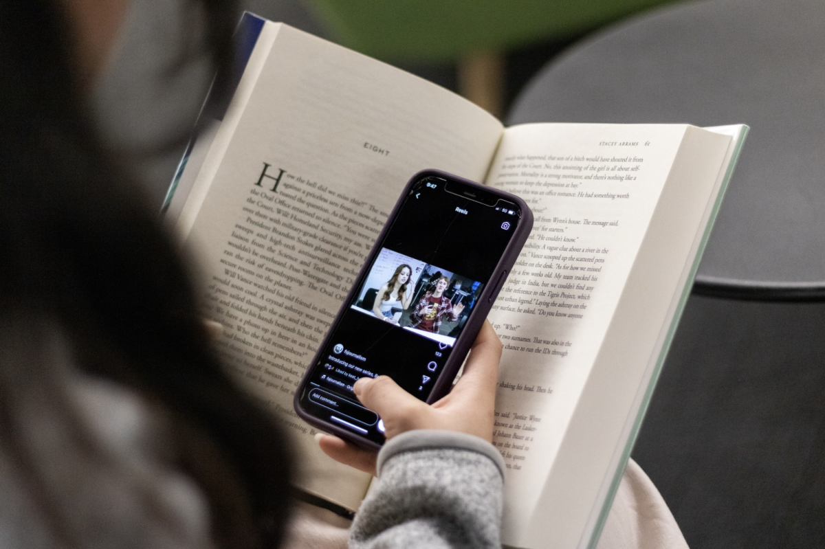 A student scrolls through Instagram while hiding their phone in a book. Many students employ similar tactics to get out of reading. 