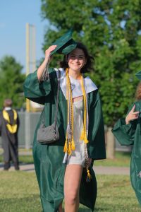Tipping her mortarboard on graduation day, senior Geneva Sabatini prepares to walk down to the field.