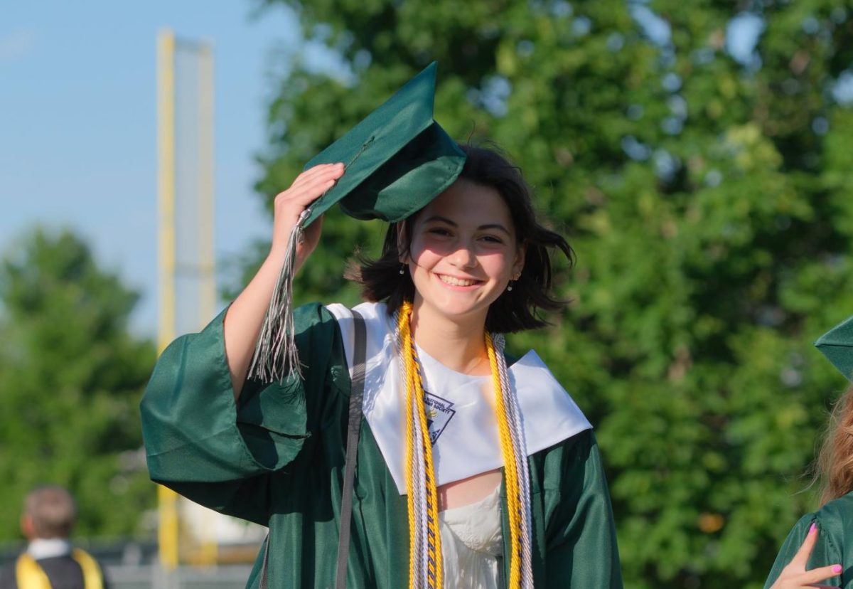 Tipping her mortarboard on graduation day, senior Geneva Sabatini prepares to walk down to the field.
