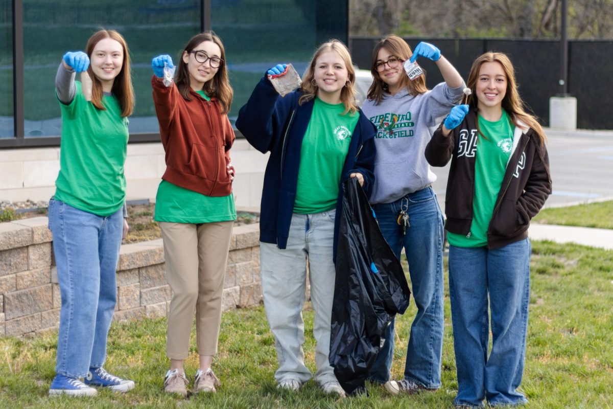 Volunteers hold up pieces of trash during the Great Green Help volunteering day for juniors.