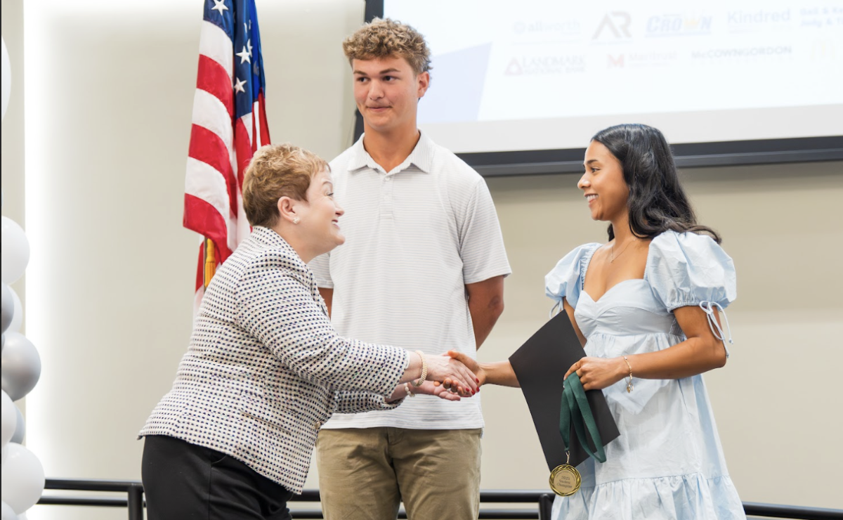 Shaking hands, superintendent Jeanice Kerr Swift honors seniors Aidan Murray and Sara Kumar.