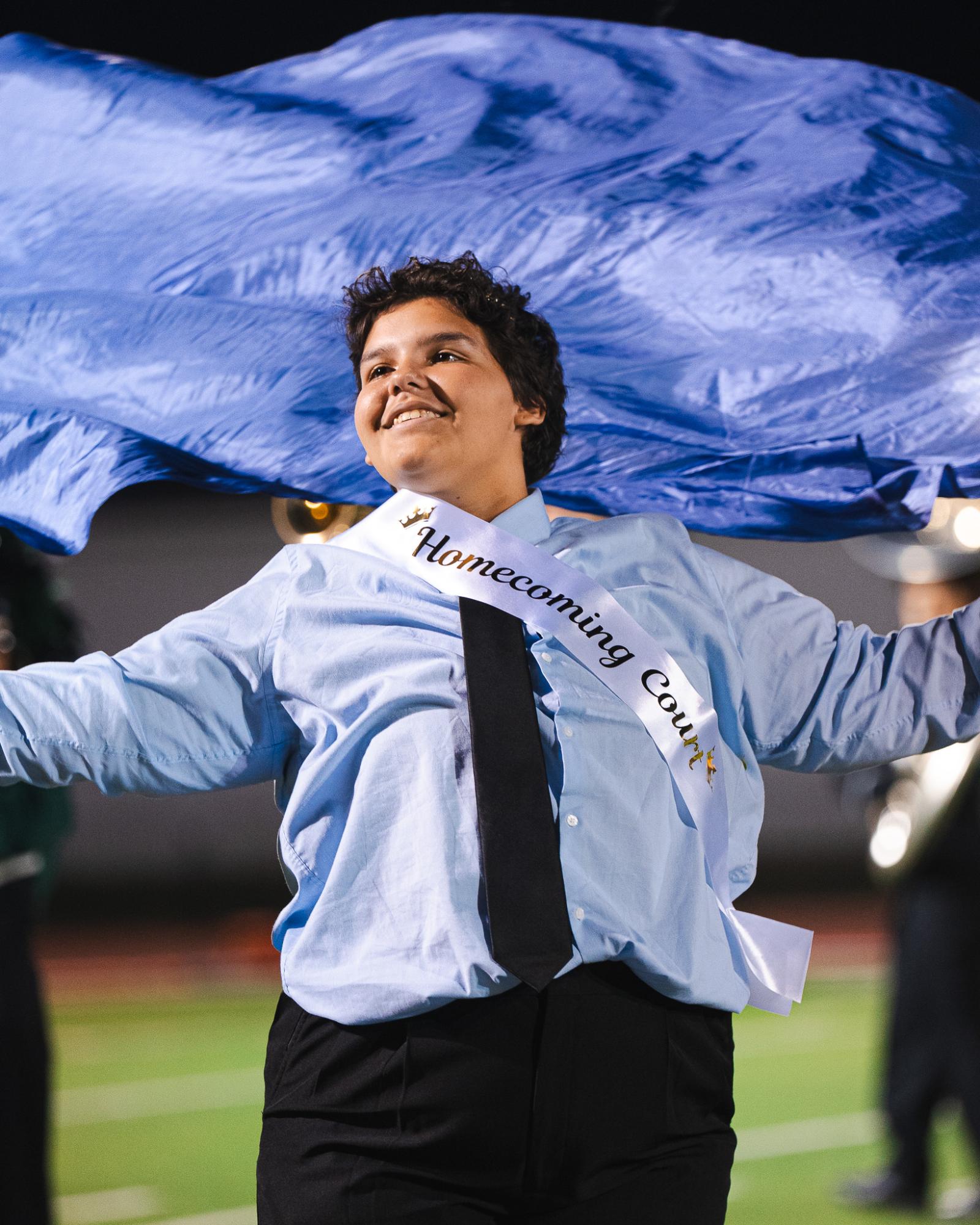 Waving his flag, senior Kouri Demelash performs his color guard routine at half time.