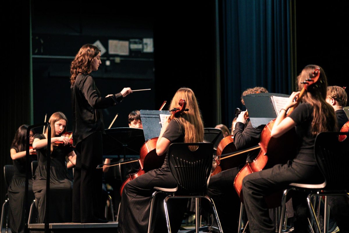 Facing the orchestra, sophomore Rory Kuhlmann conducts the Fall Orchestra Concert.
