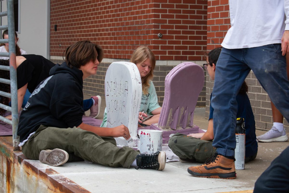 Working on the set, members of the Addams Family crew paint tomb stones.