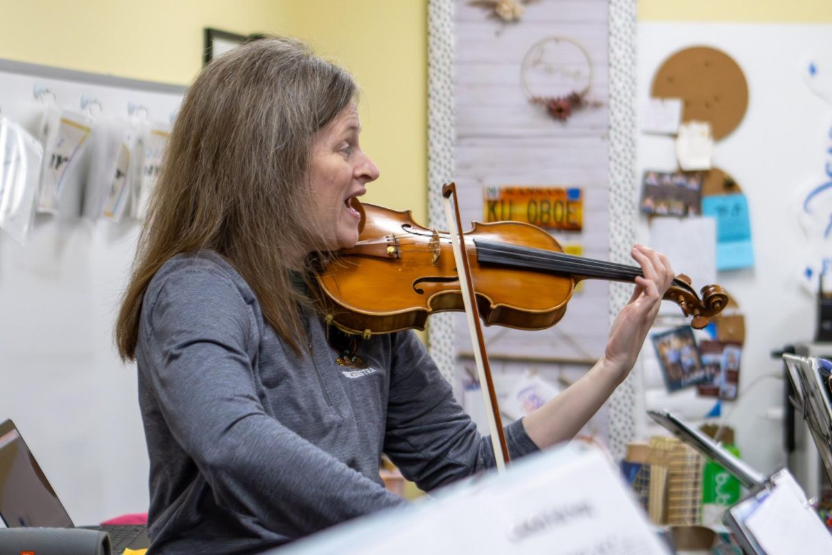 Instructing the fifth graders, orchestra teacher Ms. Herron plays the violin.
